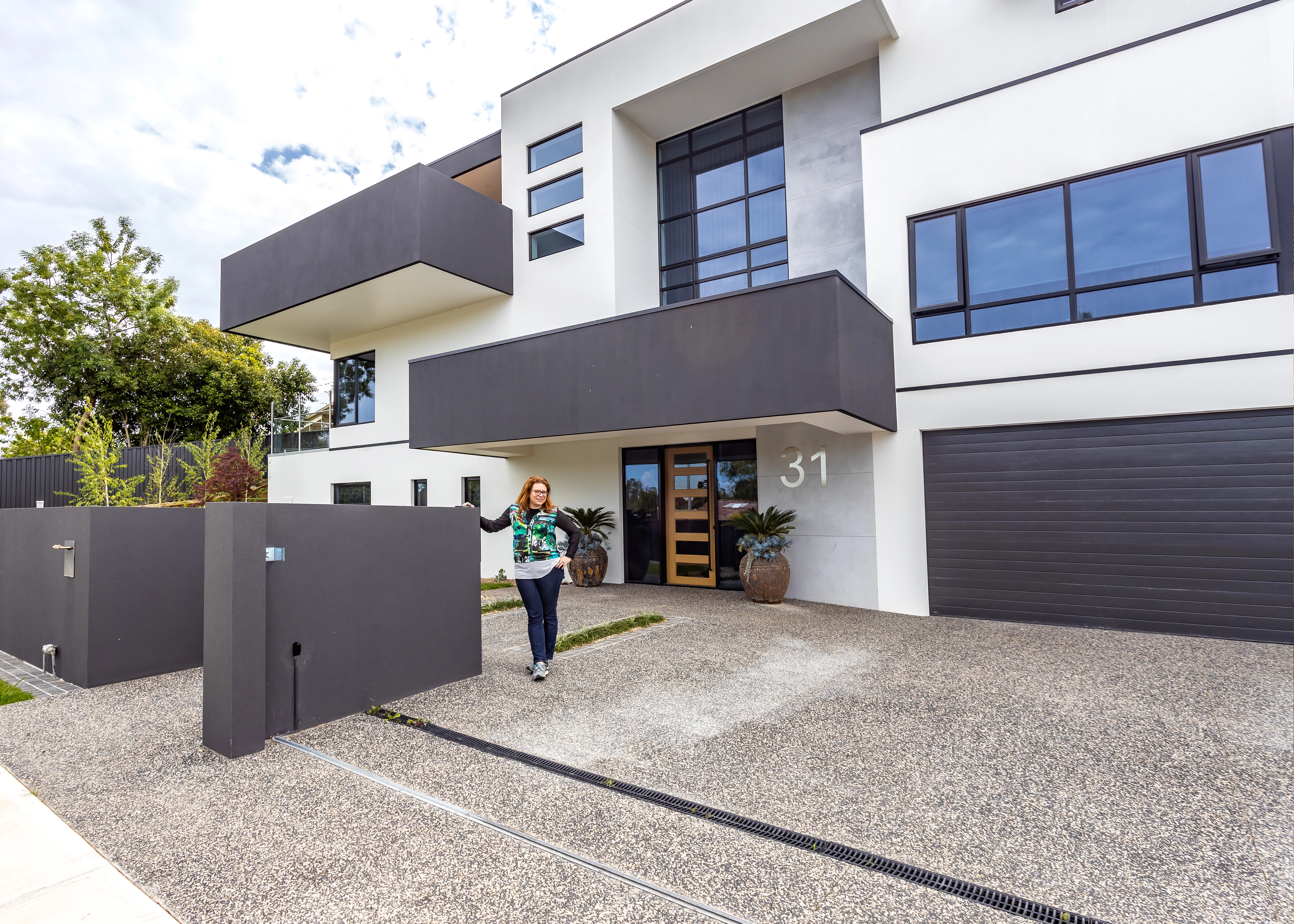 Contemporary residence with dark upper level and street fence.