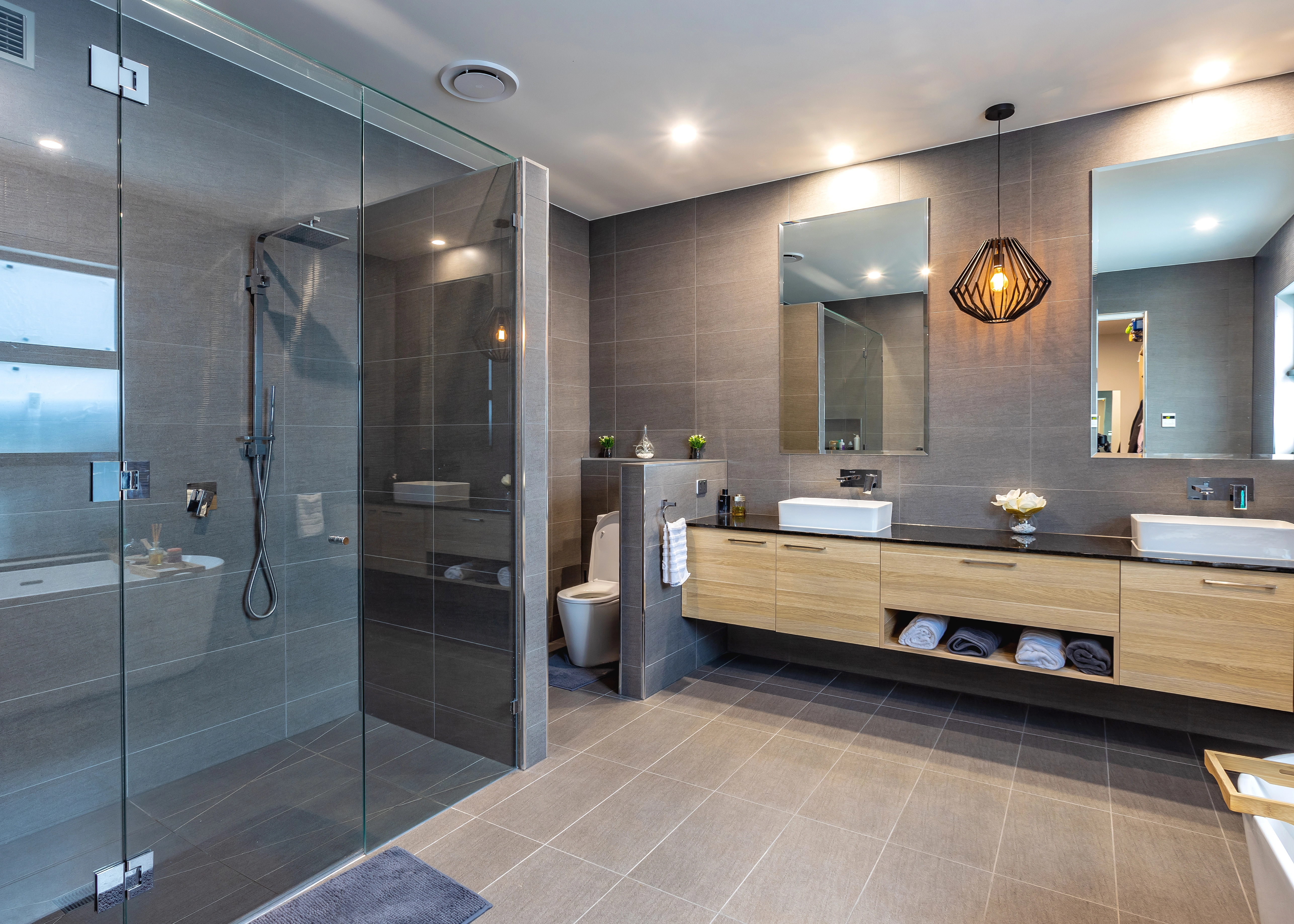 Modern ensuite with frameless glass shower, double vanity, feature pendant lighting and refined contemporary finishes.