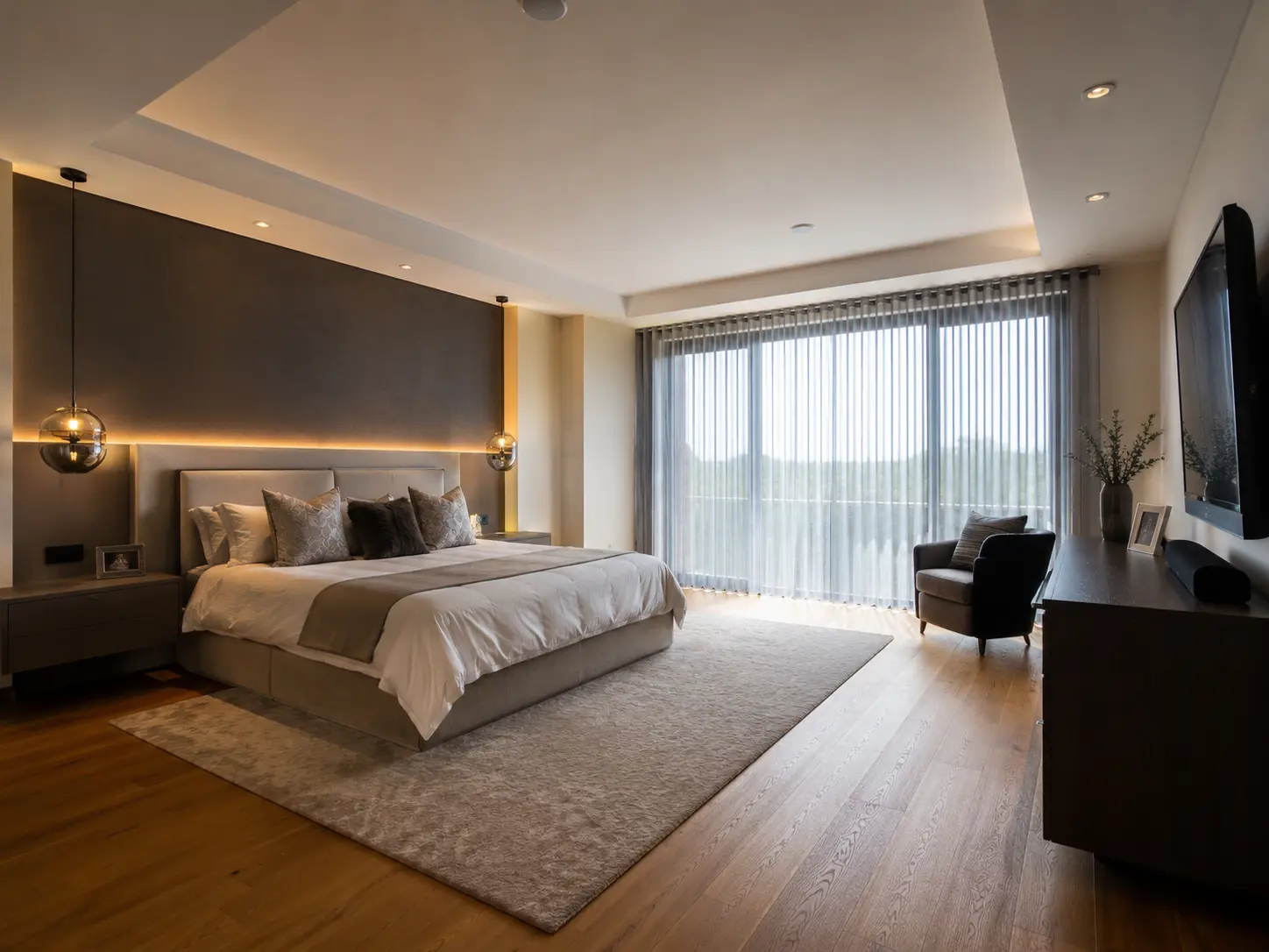 Spacious master bedroom with warm lighting, custom finishes and a calm contemporary palette.