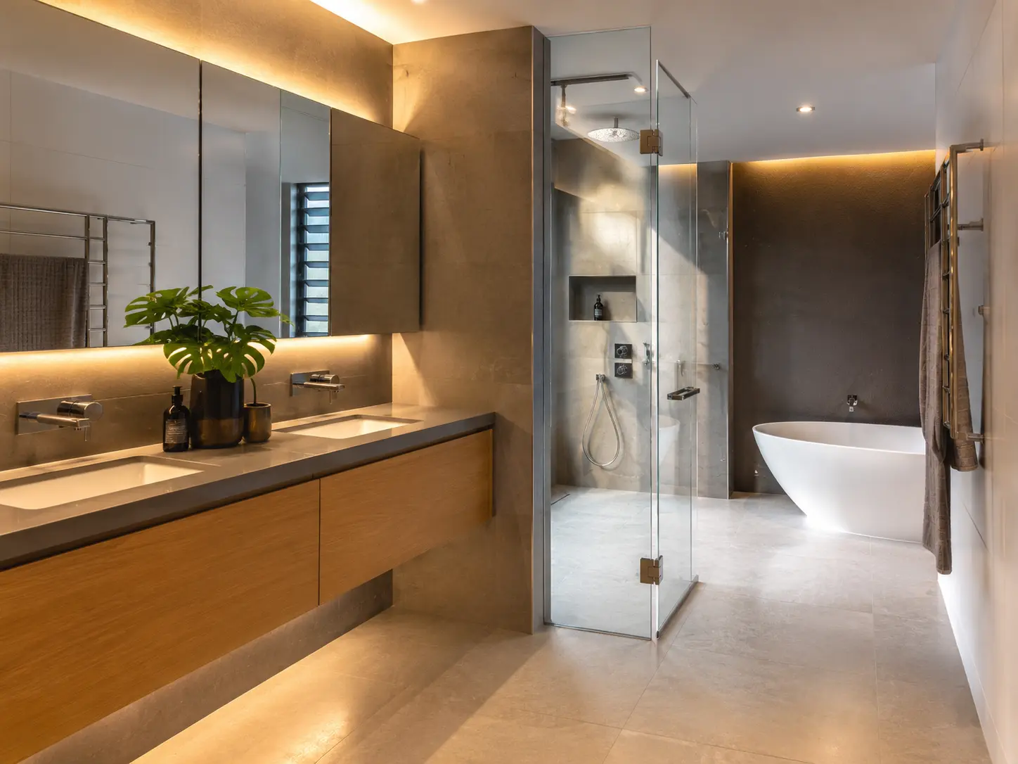 Modern guest bathroom with timber vanity, feature lighting, freestanding bath and frameless glass shower.